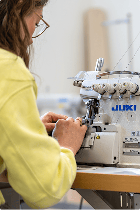 Utilisation d'une machine à coudre industrielle, illustrant la précision du travail en atelier